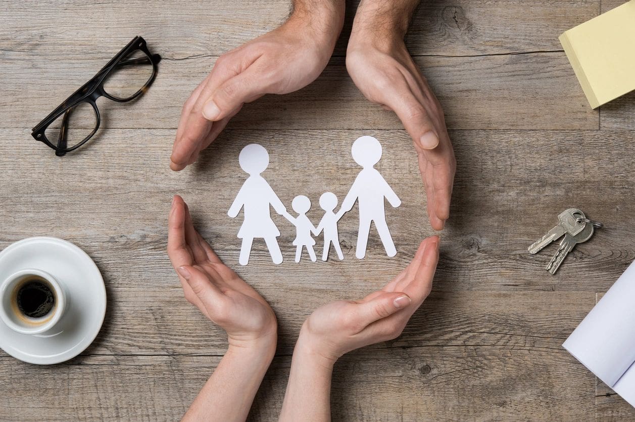 A paper cut out of a family with hands around them.